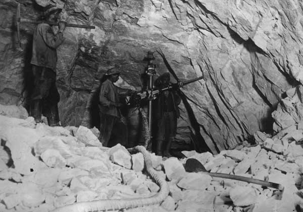 Arbeiter mit Bohrmaschine beim Bau des Lötschbergtunnels